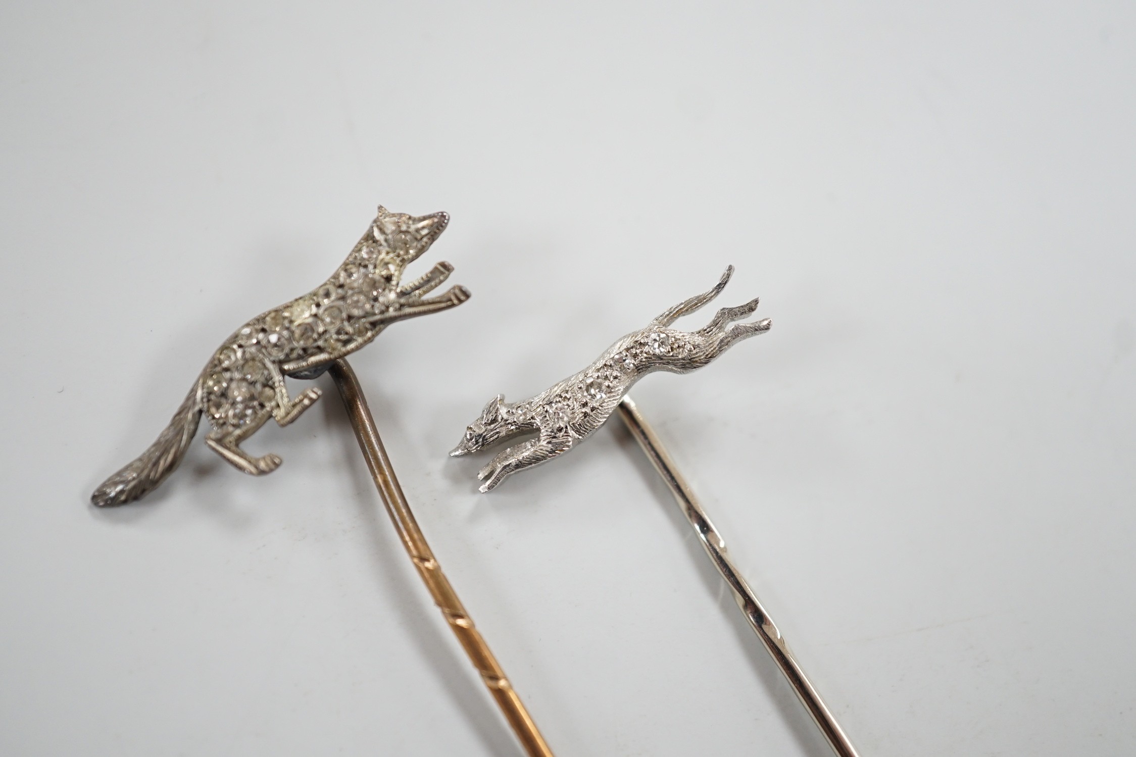 A mid 20th century white metal and diamond chip set hound stick pin, 57mm, in Asprey box and a similar paste set fox stick pin.